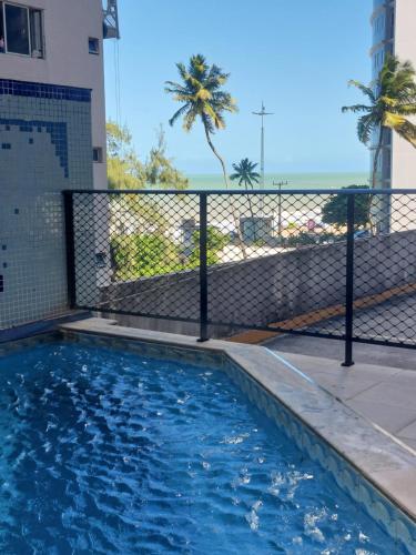 einen Pool mit einem Zaun und Palmen in der Unterkunft Lindo Apt em Boa Viagem in Recife