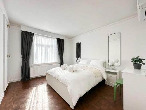 um quarto branco com uma cama grande e um espelho em London's Charm Modern 2BR Marylebone's Best Spot em Londres