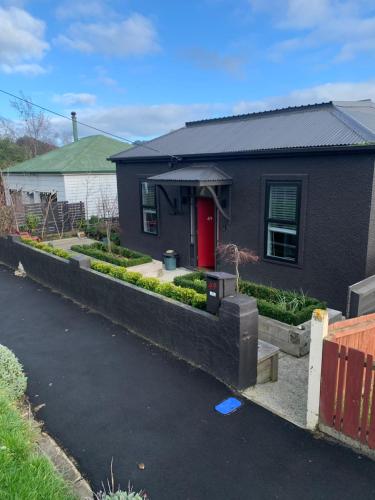 ein Haus mit einer roten Tür im Hof in der Unterkunft Roslyn Business Studio - 2 bedroom in Dunedin