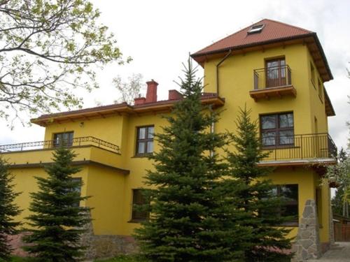 una casa amarilla con árboles delante de ella en Noclegi NADZAMCZE, en Czorsztyn