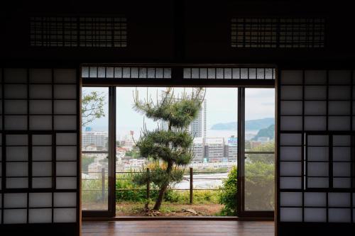 an open door in a building with a tree outside at new! 熱海桃山邸　Atami terrace villa 〜Sauna & Onsen 〜 in Atami
