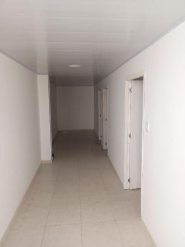 an empty hallway with white walls and a white tile floor at Hotel Romadar in Puerto López
