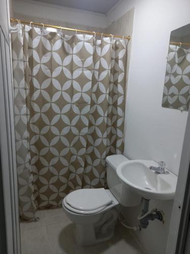 a bathroom with a toilet and a sink and a shower curtain at Hotel Romadar in Puerto López