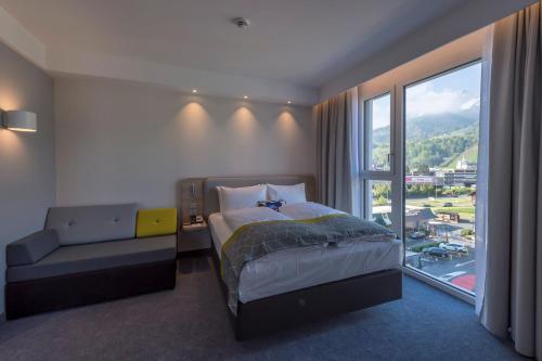 ein Schlafzimmer mit einem Bett und einem großen Fenster in der Unterkunft Holiday Inn Express - Luzern - Kriens, an IHG Hotel in Luzern