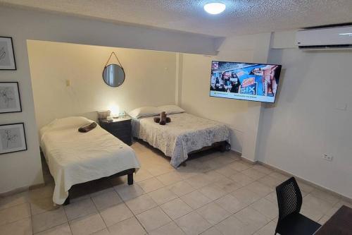 Habitación con 2 camas y TV en la pared. en Departamento ( j ) Comodo centrico Tv Ac wifi cocina parking, en Ciudad Valles