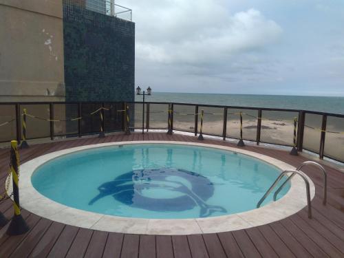uma banheira de hidromassagem em um deck com a praia ao fundo em Cobertura Duplex c/ Piscina em Salvador