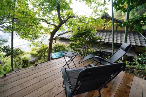 a wooden deck with two chairs and a table at new! 熱海桃山邸　Atami terrace villa 〜Sauna & Onsen 〜 in Atami
