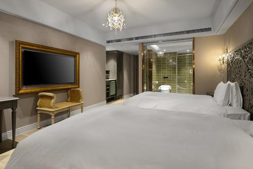 a bedroom with a large white bed and a flat screen tv at 格拉斯行館 Grasse Grace Manor 苗栗唯一SLH會員 in Nanzhuang