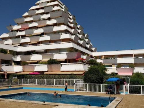 un immeuble avec une piscine devant un immeuble dans l'établissement Studio climatisé avec terrasse, piscine et parking à La Grande-Motte - 4 pers - FR-1-716-54, à La Grande Motte