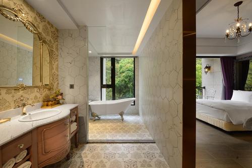 baño con bañera y lavamanos y cama en 格拉斯行館 Grasse Grace Manor, en Nanzhuang