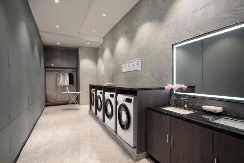 baño con 3 lavadoras y lavamanos en Yiwu Kaison K Hotel, en Yiwu