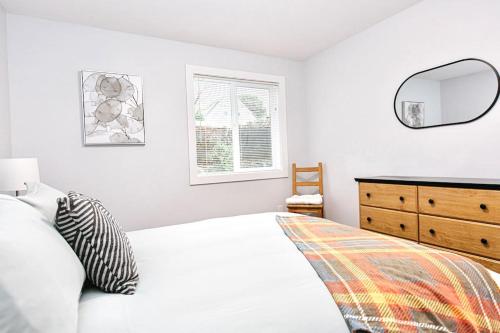 a bedroom with a bed and a dresser and a mirror at Esquimalt Lagoon Life in Victoria