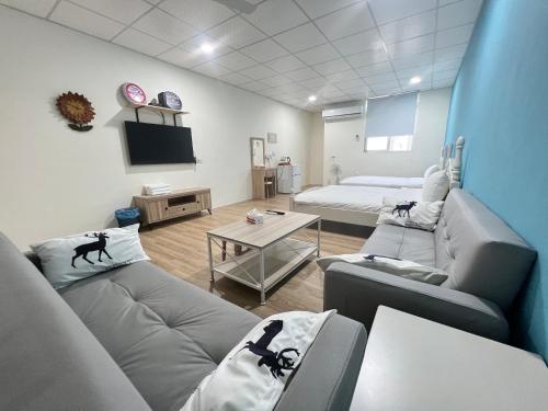 a room with two couches and a bed and a tv at Fangliao Little Swallow Light Hotel in Fangliao