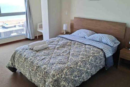 1 dormitorio con 1 cama con manta y ventana en apartamento de estreno con balcón frente al mar. en Lima
