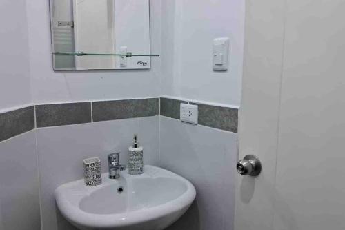 Baño blanco con lavabo y espejo en apartamento de estreno con balcón frente al mar. en Lima