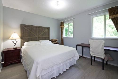 1 dormitorio con 1 cama blanca y 2 ventanas en Lake Simicoe town cottage near Innisfil Beach Park, en Innisfil