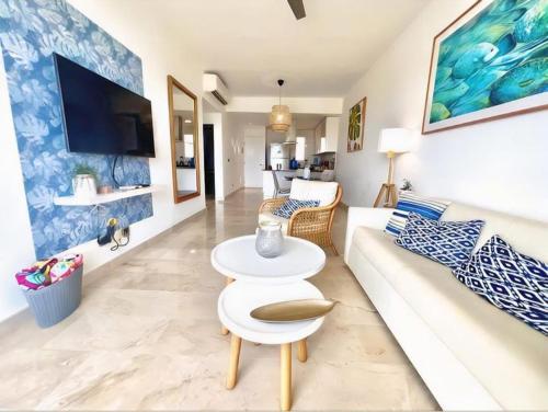 a living room with a white couch and a tv at Hard Rock at Cana Rock 2 by Unwind Properties in Punta Cana