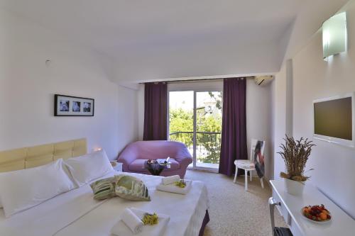 a living room with a bed and a couch and a tv at Kiraz Butik Hotel in Alaçatı