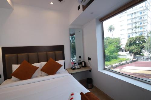 a bedroom with a bed and a large window at Goodland Elegance in Trivandrum