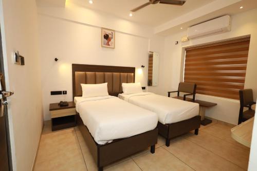 a hotel room with two beds and a desk at Goodland Elegance in Trivandrum