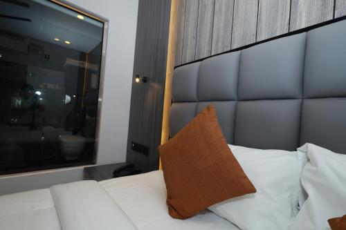 a white bed with a brown pillow on it at Goodland Elegance in Trivandrum