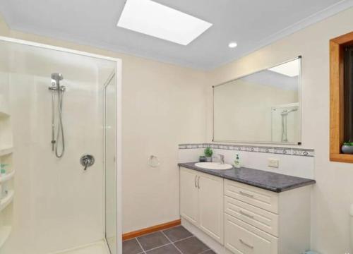 een badkamer met een wastafel en een spiegel bij Home @ Scamander Beach in Scamander