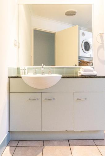 a bathroom with a sink and a large mirror at Beaches Holiday Apartments - Official Onsite Reception & Check In in Port Douglas