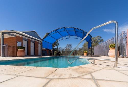 a swimming pool with a blue arch and a slide at Albert Motel in Moree