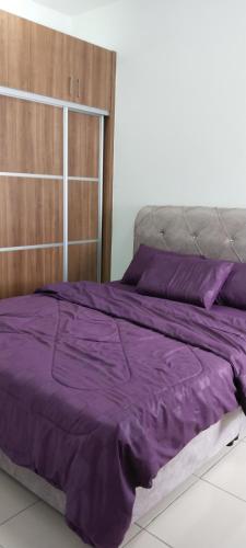 1 cama con sábanas moradas y cabecero de madera en MQA Homestay en Sepang