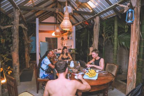 eine Gruppe von Menschen, die um einen Tisch herum sitzen in der Unterkunft Shady Cottage in Ahangama