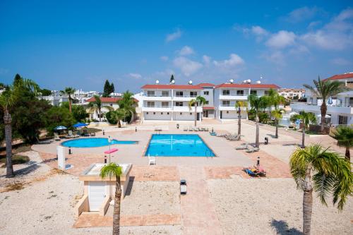 a view of a resort with a swimming pool and palm trees at Narcissos 'Nissi Beach' Apartment E9 in Ayia Napa