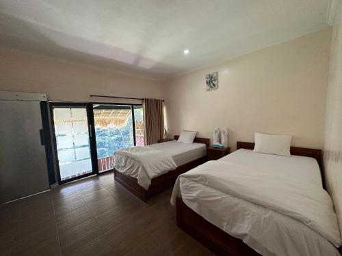 ムンドゥックにあるMunduk Tutub waterfall viewのベッド2台と窓が備わるホテルルームです。