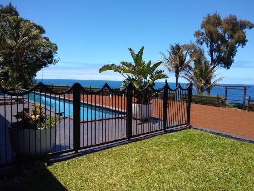 ein schwarzer Zaun mit Bäumen und einem Pool in der Unterkunft Hale Laule'a at Opihi Point - Oceanfront, Gated Estate in Hakalau