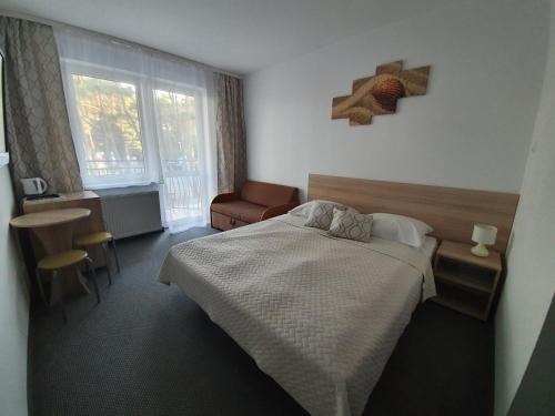 um quarto com uma cama, uma mesa e uma cadeira em The White House Dom Wypoczynkowy em Pogorzelica