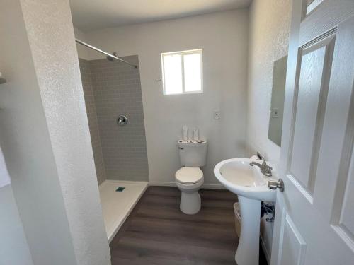 a white bathroom with a toilet and a sink at Palm Inn in Mojave