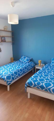 twee bedden in een kamer met een blauwe muur bij Chez Malo 