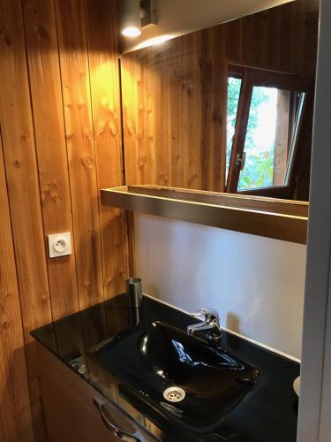 une salle de bain avec un lavabo noir et un miroir dans l'établissement Chalet dans plusieurs hectares de nature, à Barjols