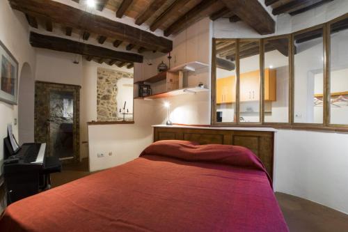 - une chambre avec un lit rouge et un piano dans l'établissement Appartamento nel Borgo, à Roccatederighi