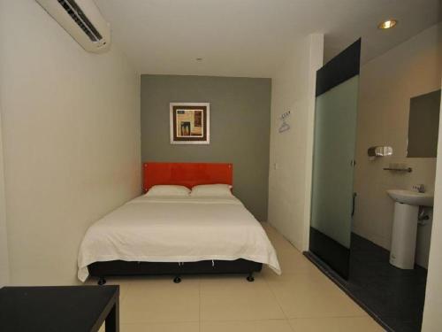 a bedroom with a bed with a red headboard and a sink at M Design Hotel @ Pandan Indah in Kuala Lumpur