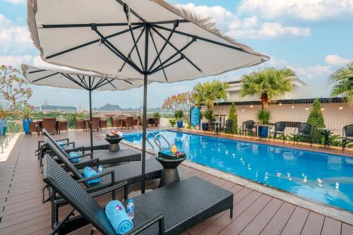 a pool with two tables and an umbrella at Grand Fleuve Boutique in Ha Long