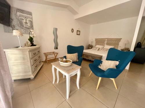 a bedroom with a bed and blue chairs and a table at La maison de la Cigale in Forcalqueiret