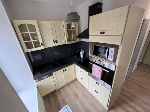a small kitchen with white cabinets and a microwave at Appartement centre-ville de Lure gauche in Lure
