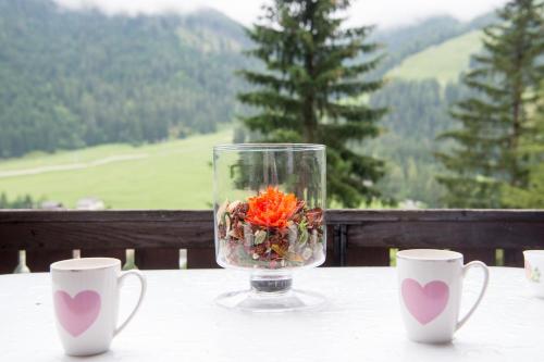 a vase with flowers in it on a table with two cups at 5 room house Joch Churwalden- Lenzerheide in Churwalden