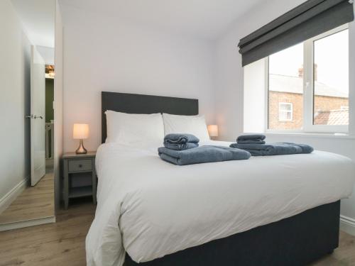 um quarto com uma grande cama branca com toalhas em 2 Staveley Cottages em Weaverthorpe