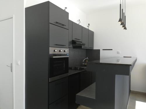 a kitchen with black cabinets and a stove top oven at Résidence ÉBÈNE - Villas in Antsakomboena