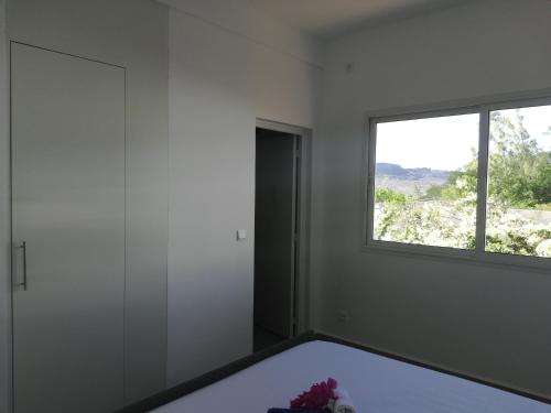 biały pokój z oknem i łóżkiem w obiekcie VILLA FLEUR d'EBENE w mieście Antsakomboena