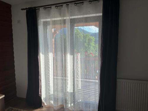a window with curtains with a view of a balcony at Casa Maramureșană in Vişeu de Sus