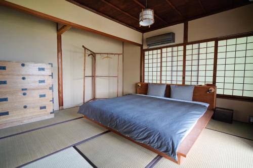 a bedroom with a blue bed in a room with windows at new! 熱海桃山邸　Atami terrace villa 〜Sauna & Onsen 〜 in Atami