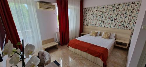 a bedroom with a bed with a red blanket at OITUZ Boutique Residence in Mangalia