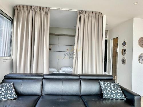 - un salon avec un canapé en cuir en face d'une fenêtre dans l'établissement Le Yacht YourHostHelper, à Deauville